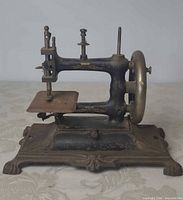 Left side and base of cast iron Muller child’s sewing machine