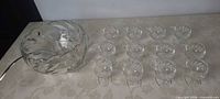 Large clear glass punch bowl and twelve matching cups laid out