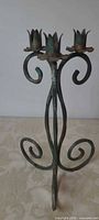 Full view of green metal candle holder showing three cups and scroll design