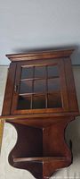 Front view of wood corner cupboard showing glass-pane door and lower open shelf