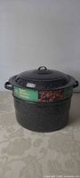 Front view of black speckled enamel canning pot with lid and label visible