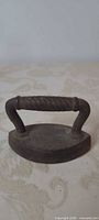 Oblique view showing full miniature sad iron with twisted handle