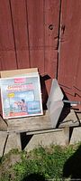 Boxed Imperial Universal Aluminum Chimney Cap beside used cap on bench