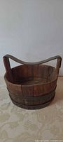 Front view of round wooden bucket with leather handle and metal bands