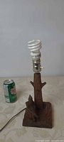 Full view of carved wooden lamp with CFL bulb beside soda can for scale