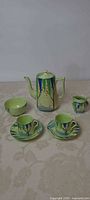 Full tea set displayed: teapot, sugar bowl, creamer, two cups, two saucers