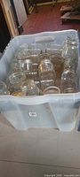 Plastic tote holding numerous clear glass canning jars of varying sizes