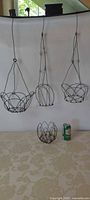 Three hanging wire baskets and one bowl holder with soda can for scale