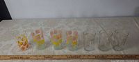 Seven juice glasses lined up with ruler for scale
