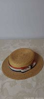 Full view of straw boater hat showing ribbon band and overall shape