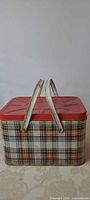 Full view of picnic hamper showing plaid sides, red lid, dual handles