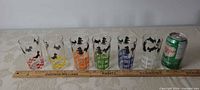 All six glasses with colour bands red, yellow, orange, green, blue, dark blue, with ruler and can for scale