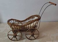 Side view of wicker doll carriage showing wheels and handle