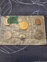 Front view of sealed 1991 coin set showing six coins in cellophane and handwritten year tag