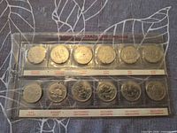 Reverse designs of 12 commemorative 25-cent coins in labeled plastic holder