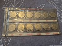 Front view of 12 commemorative reverse designs in labeled plastic sleeve