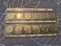 Front view of 12 Millennium coins in labeled plastic holder showing themes