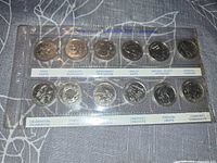 Front view of the 12-coin set in plastic holder, themes visible