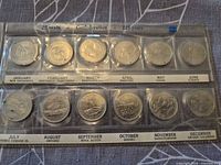 Front of plastic holder showing twelve provincial/territorial quarters in labeled slots January–December.