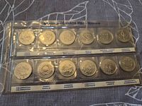 Front view of 12-coin Millennium 2000 quarter set in plastic holder showing themed reverse designs