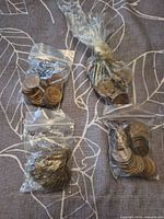Four plastic bags of assorted Canadian pennies on cloth background