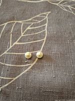Two round white freshwater pearls on fabric background