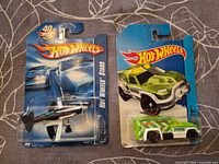Front view of both carded Hot Wheels items: Mad Propz airplane and green Rescue Duty truck