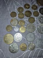 Group of mixed brass and silver-tone tokens and coins on fabric background