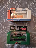 Front view of both boxed M2 Machines cars: orange EMPI VW pickup above green Turtle Wax Road Runner