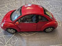 Left side and front view of red 1:18 Volkswagen New Beetle model car showing overall condition