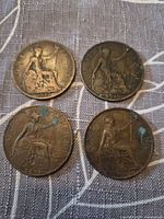 Reverse of four bronze One Penny coins with Britannia and visible dates