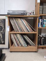 Front view of manufactured wood cabinet holding records; turntable and contents not included