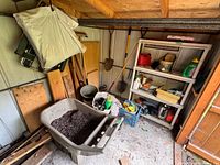 Overall shed view showing cart, lawn chair, shovels, shelving and containers