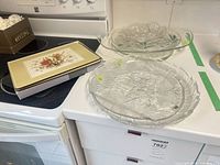Three clear glass platters stacked with box of placemats visible