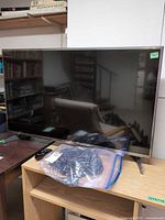 Front view of LG 42" TV on stand with remote and bag of cables visible