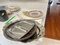 Stack of assorted metal trays with china platters visible