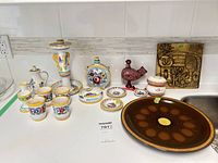 Overall view of hand-painted pottery lot with charger, plaque, candlestick, flask, cups, bird figurine, dishes