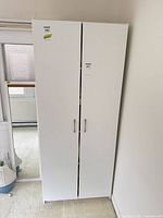 Front view of white laminate cupboard with closed double doors