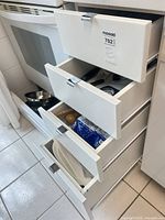 Four drawers partially open beside stove showing contents