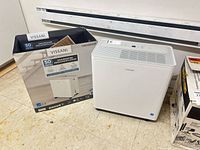 Dehumidifier beside its retail box showing branding and model