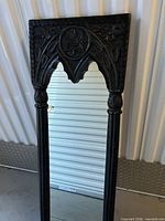 Full view of carved wood Gothic accent mirror standing upright