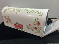 Left side view of mailbox displaying floral artwork and scale reference