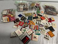 Overview showing three zipper bags filled with matchbooks and loose matchbooks spread out