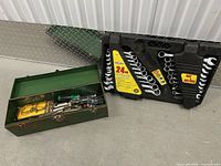 Wrench set in case beside closed green toolbox