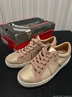 Pair of sneakers in front of original box, overall view