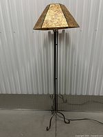 Full view of metal tripod floor lamp with copper shade