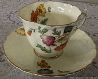 Teacup on saucer showing floral poppy design and gold trim