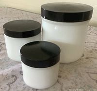 Three milk glass jars with lids standing upright