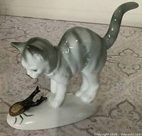 Side view of porcelain cat figurine with beetle