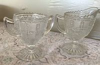 Front view of creamer and sugar bowl showing pattern and pedestal bases